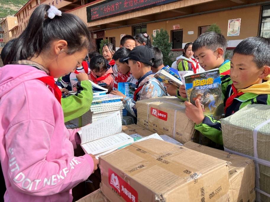 ▲川主寺镇第一小学的学生们翻阅“为你读书”公益行动送来的5000册书籍。 小龙/摄