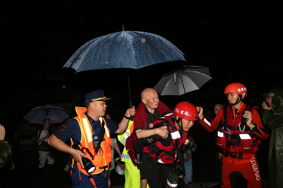 6月18日晚，消防救援人员在福建省松溪县一处村庄转移被困群众。 （李典利 摄）