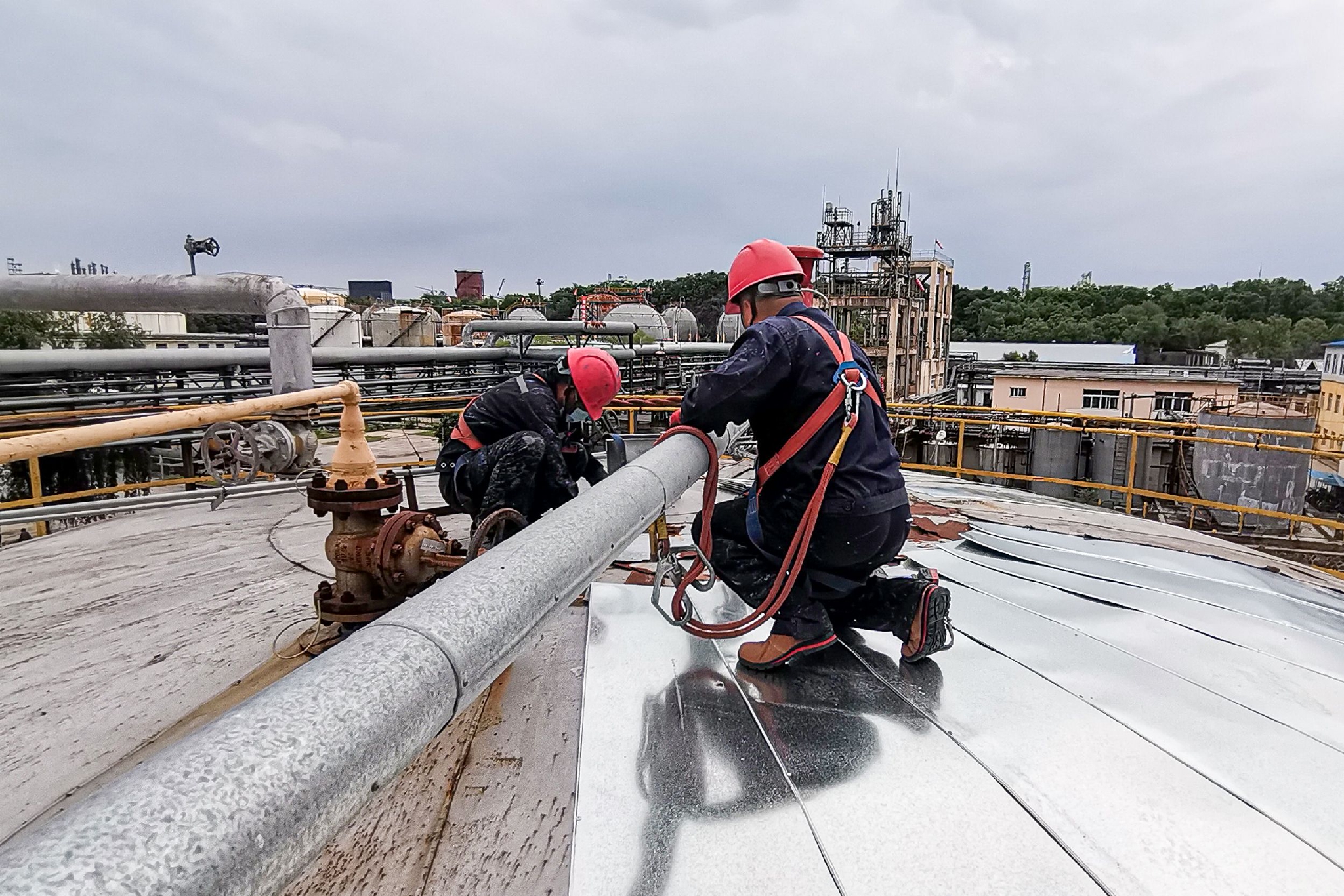 施工人员冒高温在罐顶进行保温作业