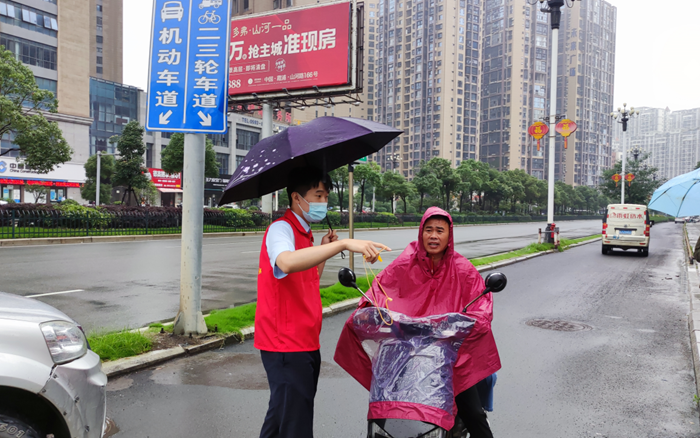 新时代文明实践志愿者在街头劝导行人佩戴头盔.陈冬冬摄