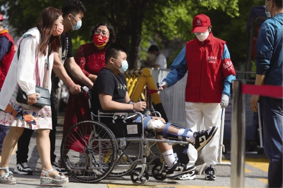 6月25日，在沈阳市浑南区一中考点，一位膝盖受伤的考生坐着轮椅进考场。辽沈晚报记者 查金辉 摄