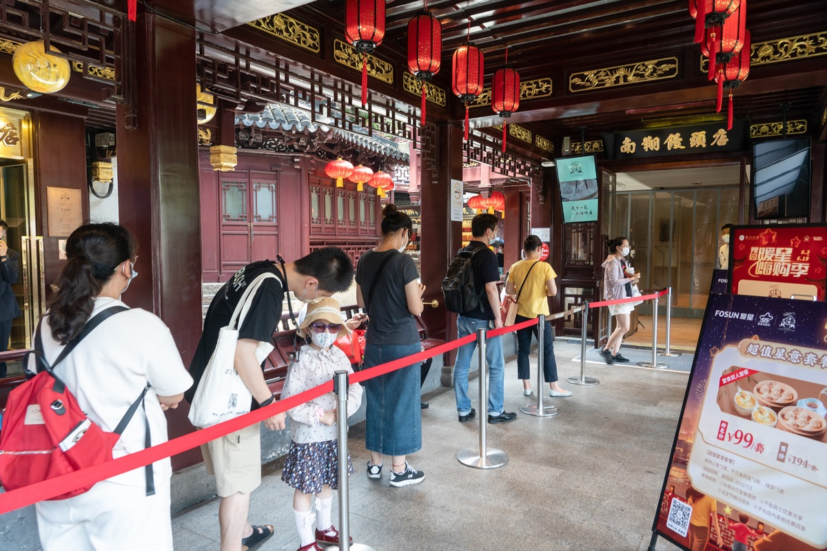 上海豫园商城，顾客在城隍庙老字号南翔馒头店外排队等候用餐。（中国日报记者 高尔强 摄）
