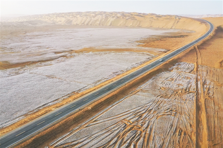 6月26日拍摄的尉犁至且末沙漠公路，工作车辆在路面行驶（无人机照片）。新华社记者 李响 摄