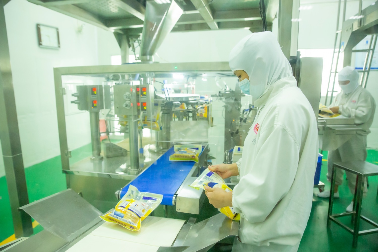 河北西麦食品有限公司复合车间内,工人正在自动称重包装机前检验包装