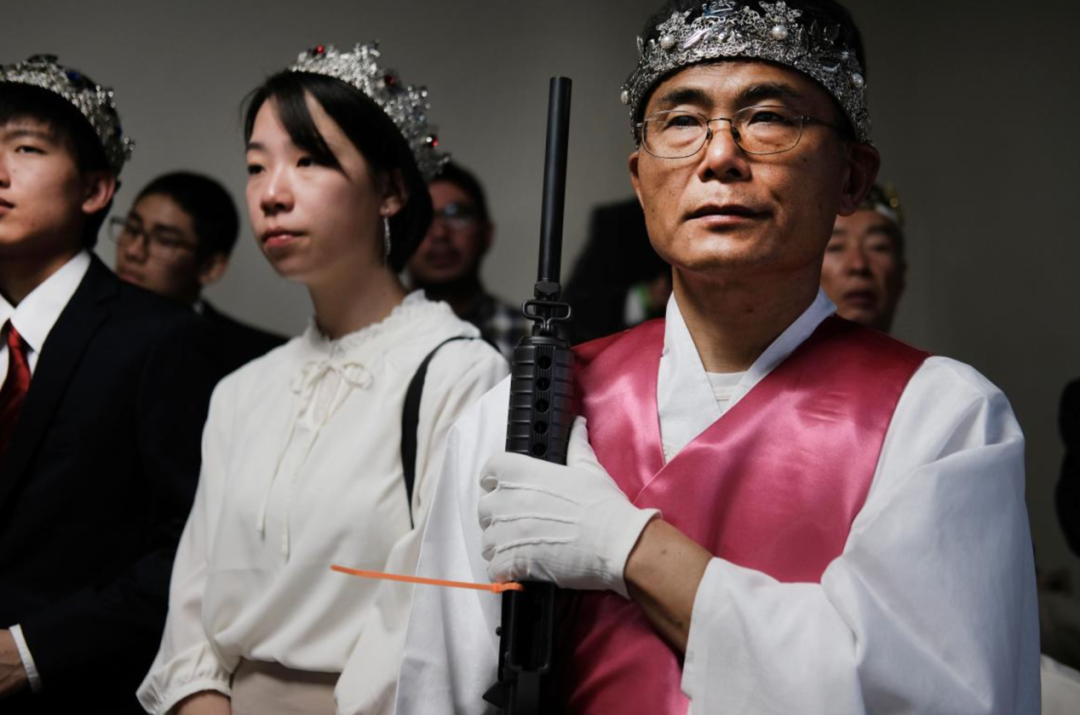 ▲在美国宾夕法尼亚州的集体婚礼上，“铁杖圣会”一名信徒手持一支AR-15步枪 来源：《泰晤士报》