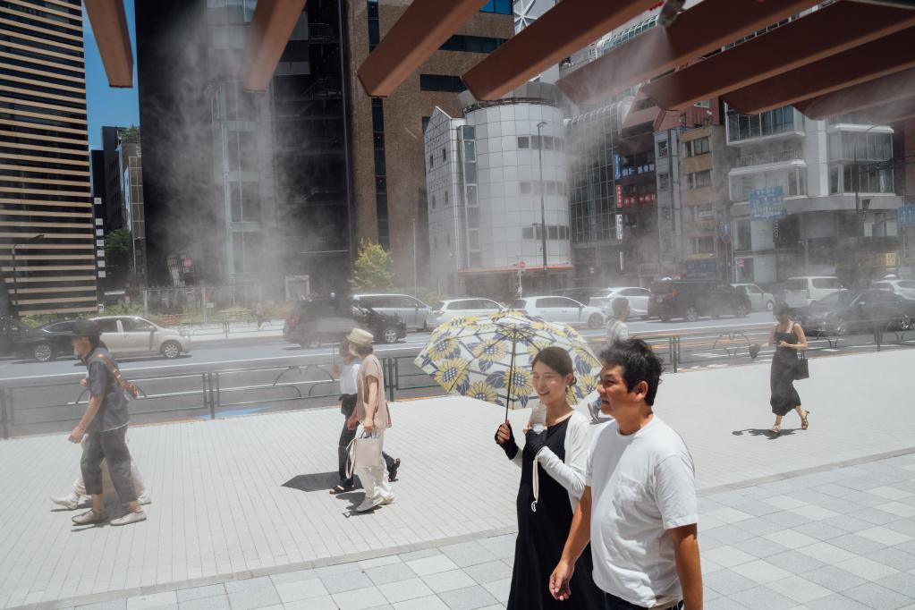2022年6月26日，行人走过日本街头的喷水消暑装置。（新华社记者张笑宇摄）
