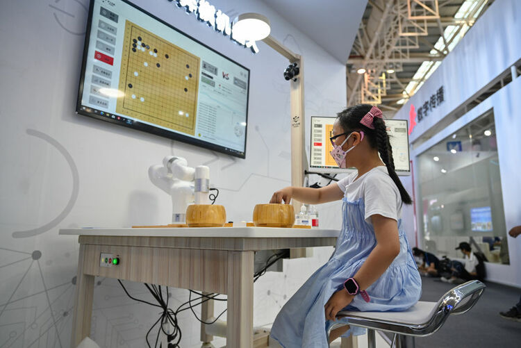 ↑7月22日，小朋友在第五届数字中国建设成果展览会上和AI机器人下棋。新华社记者 周义 摄