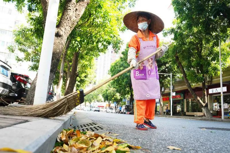 马路上,环卫工人在高温酷暑下清扫落叶.赖基润/摄