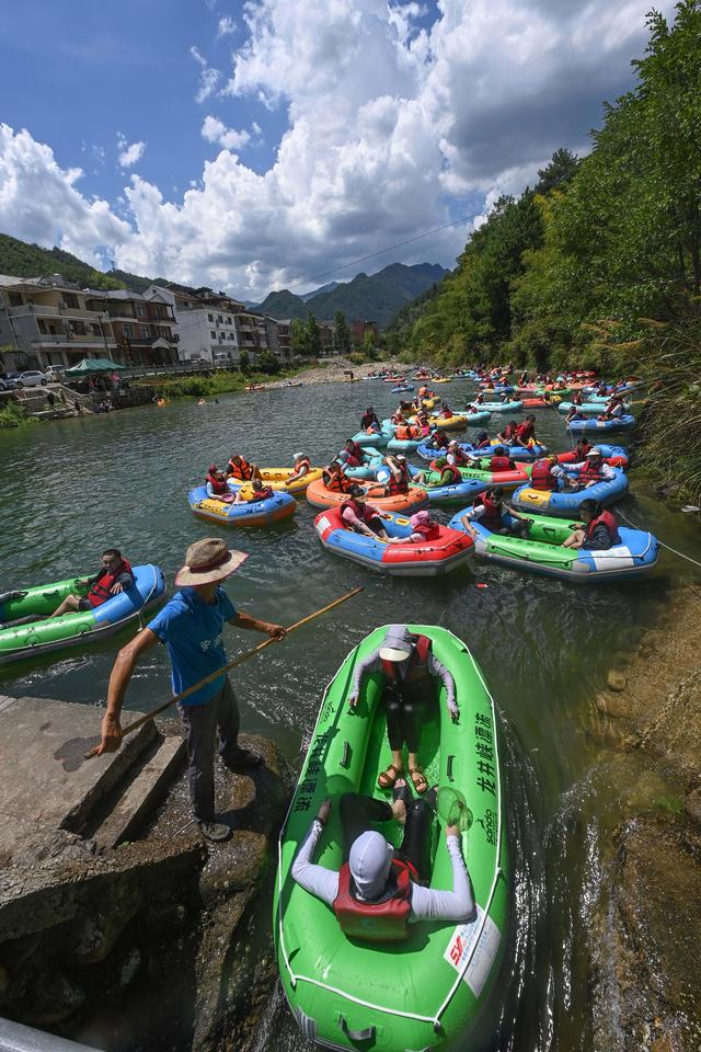 8月6日,在杭州市临安区龙岗镇龙井村的合溪旁,工作人员引导漂流的游客