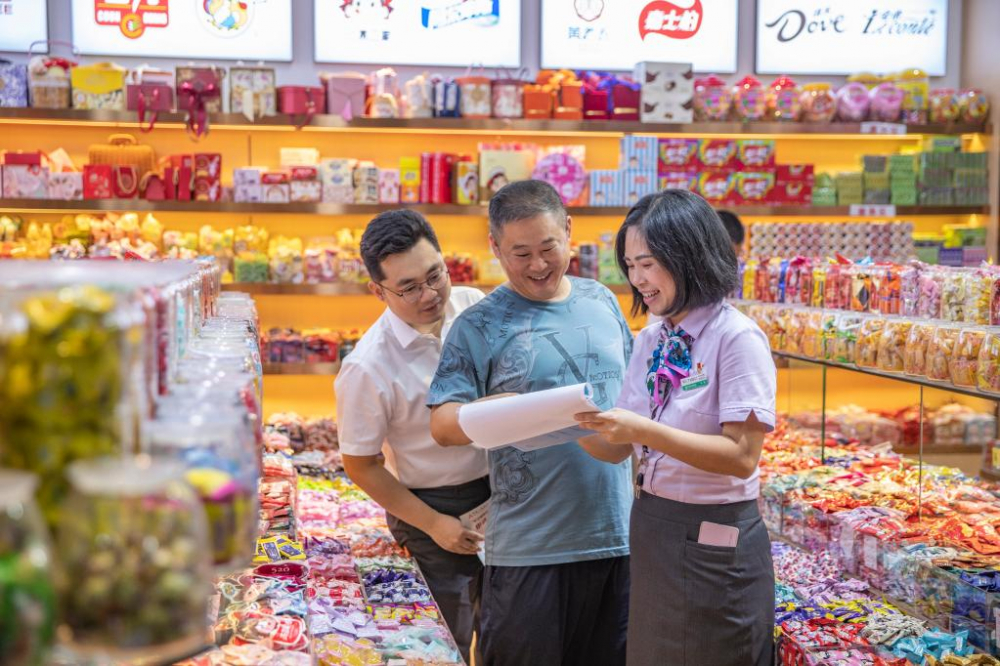 金融服务港湾工作人员对刘刚的糖果铺进行回访。新华社记者 黄伟 摄