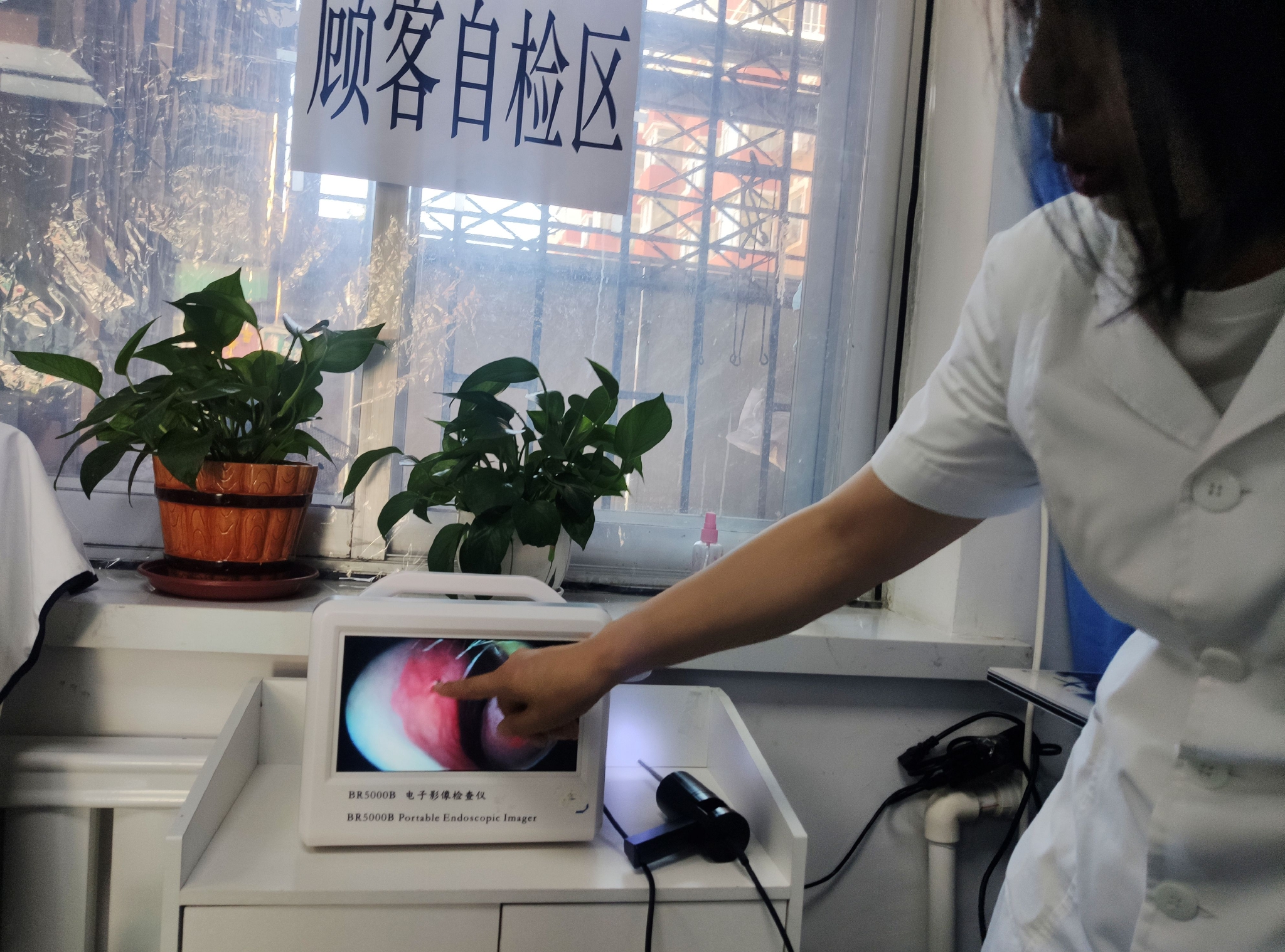身穿白大褂的女子使用电子影像设备为记者做鼻腔检查.李洪涛/摄
