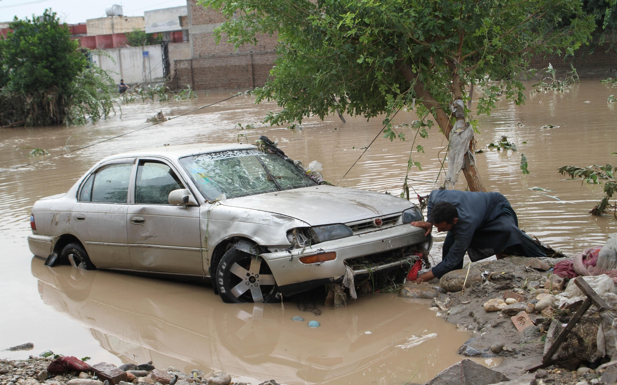 ▲8月15日，在阿富汗楠格哈尔省，一名男子查看受损车辆。图/新华社