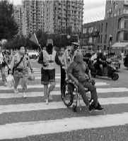 志愿者和交警帮轮椅男子过马路。