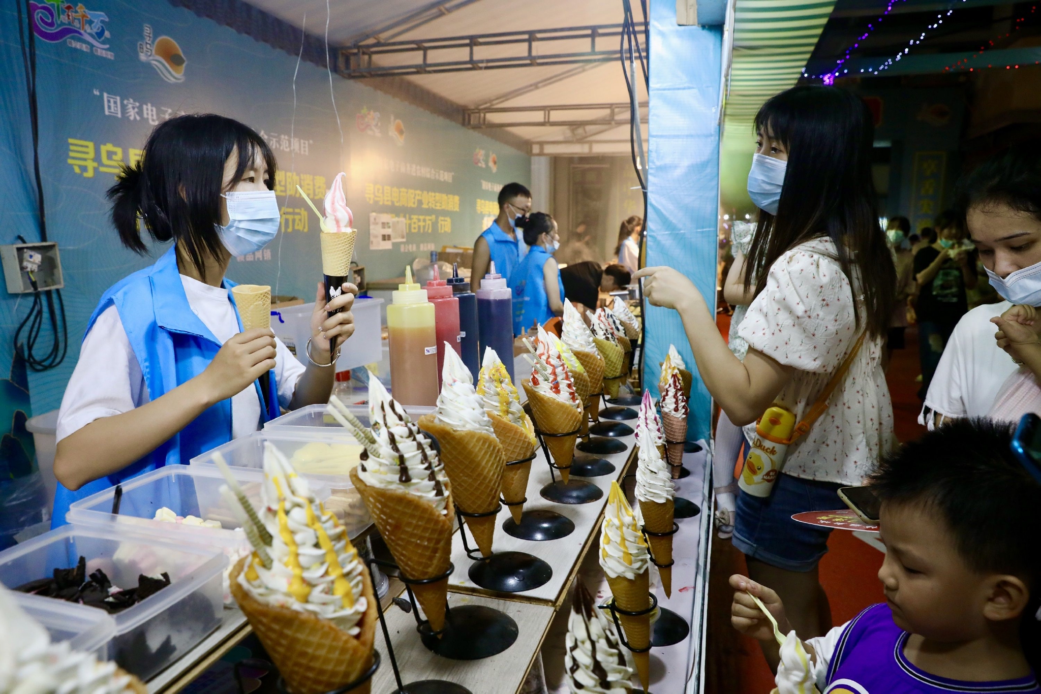 8月27日晚，在江西省寻乌县国际商贸城，游客在活动现场购买冰淇淋。中国日报记者 朱兴鑫 摄