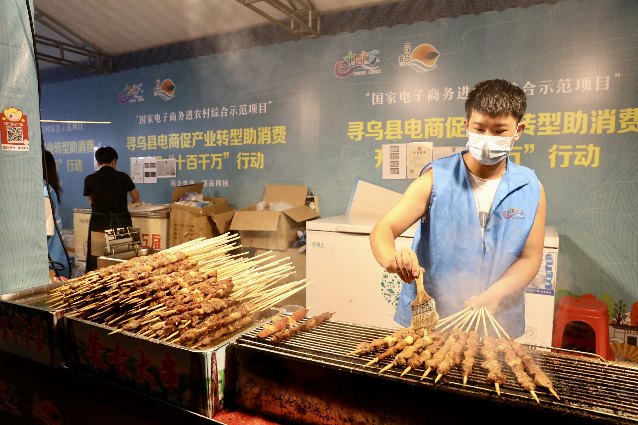 8月27日晚，在江西省寻乌县国际商贸城，工作人员在活动现场烤羊肉串。中国日报记者 朱兴鑫 摄