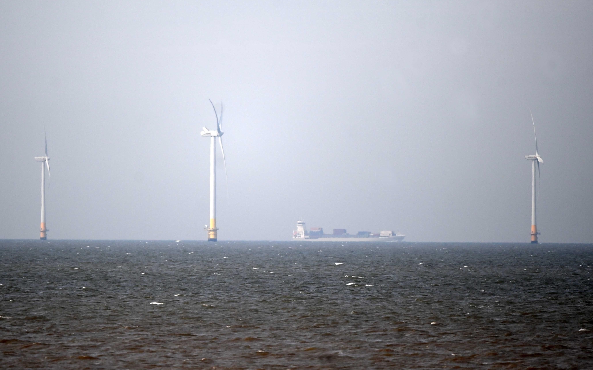 当地时间2022年4月11日，英国肯特郡，一艘船经过惠斯塔布湾附近的海上风电场。图/IC photo