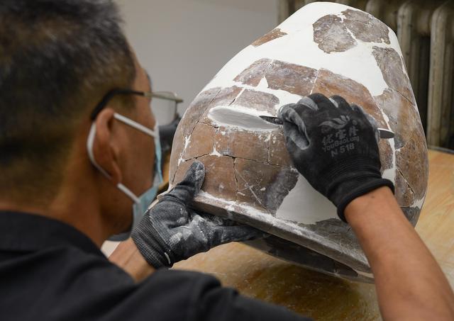 文物工作者对南佐遗址内出土的陶器进行修复(8月25日摄).