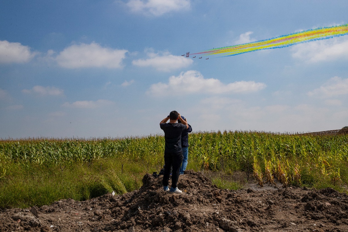 8月30日，长春大房身机场外的一处玉米地，航空爱好者拍摄“红鹰”飞行表演队的拉烟表演。（中国日报记者 匡林华 摄）