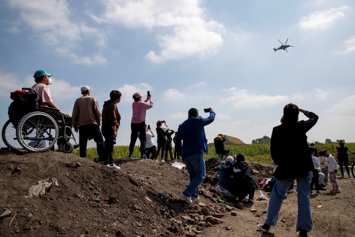 8月30日，航空爱好者利用一处渣土堆形成的高地观看拍摄武装直升机盘旋飞过。（中国日报记者 匡林华 摄）