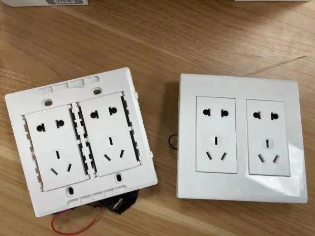 一个看似正常的白色五孔插座,背后居然用黑胶带绑着一个伪装摄像设备