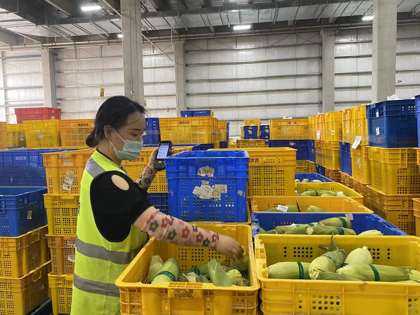 美团优选工作人员正在分拣,搬运商品 图片来源:企业供图