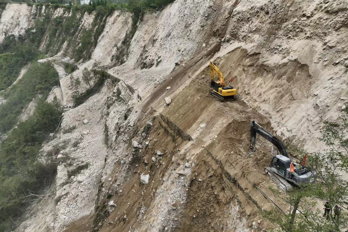 9月6日，泸定县磨西镇通往海螺沟景区的道路被山体滑坡阻断，蜀道集团工作人员通过挖机在绝壁之上全力抢通道路。（杨树 摄）