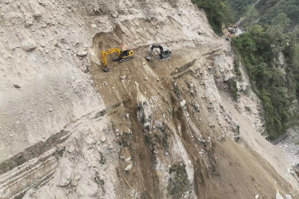 9月6日，泸定县磨西镇通往海螺沟景区的道路被山体滑坡阻断，蜀道集团工作人员通过挖机在绝壁之上全力抢通道路。（杨树 摄）