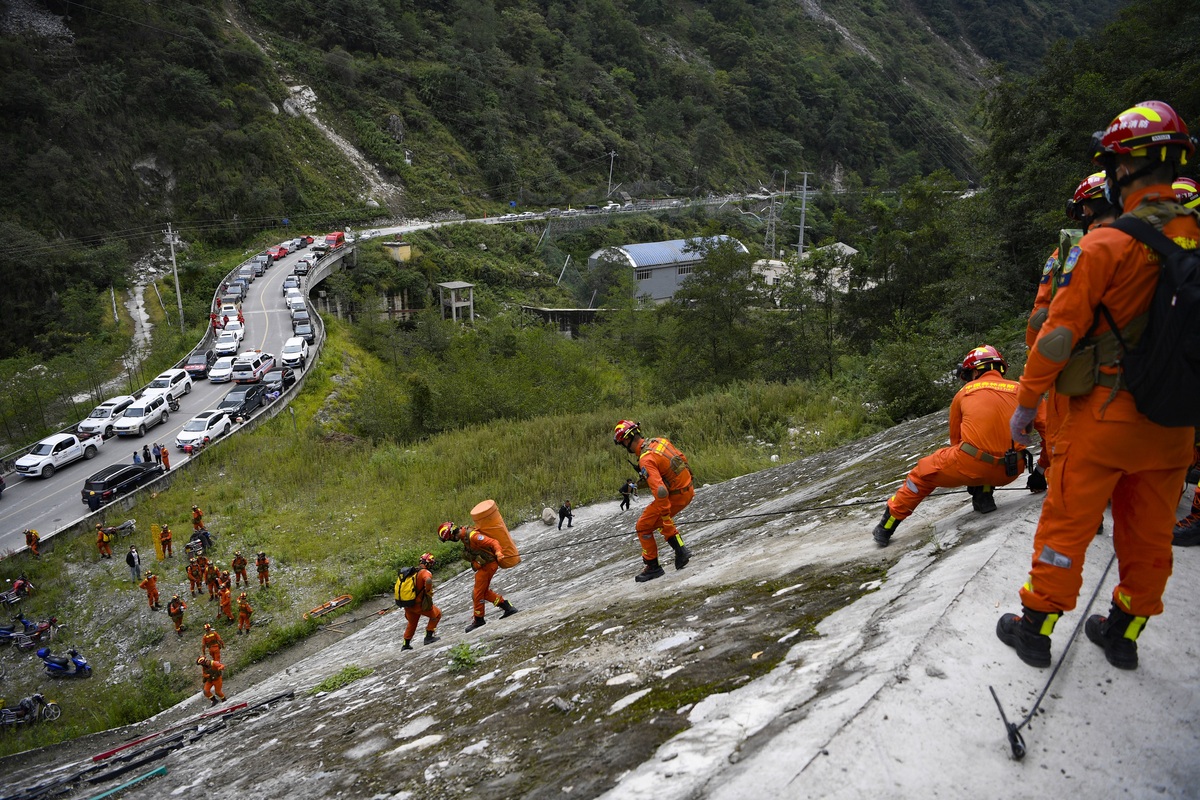9月6日，救援途中遭遇断道，四川省森林消防总队特勤大队队员们顺着绳索爬到坡底。（杨树 摄）