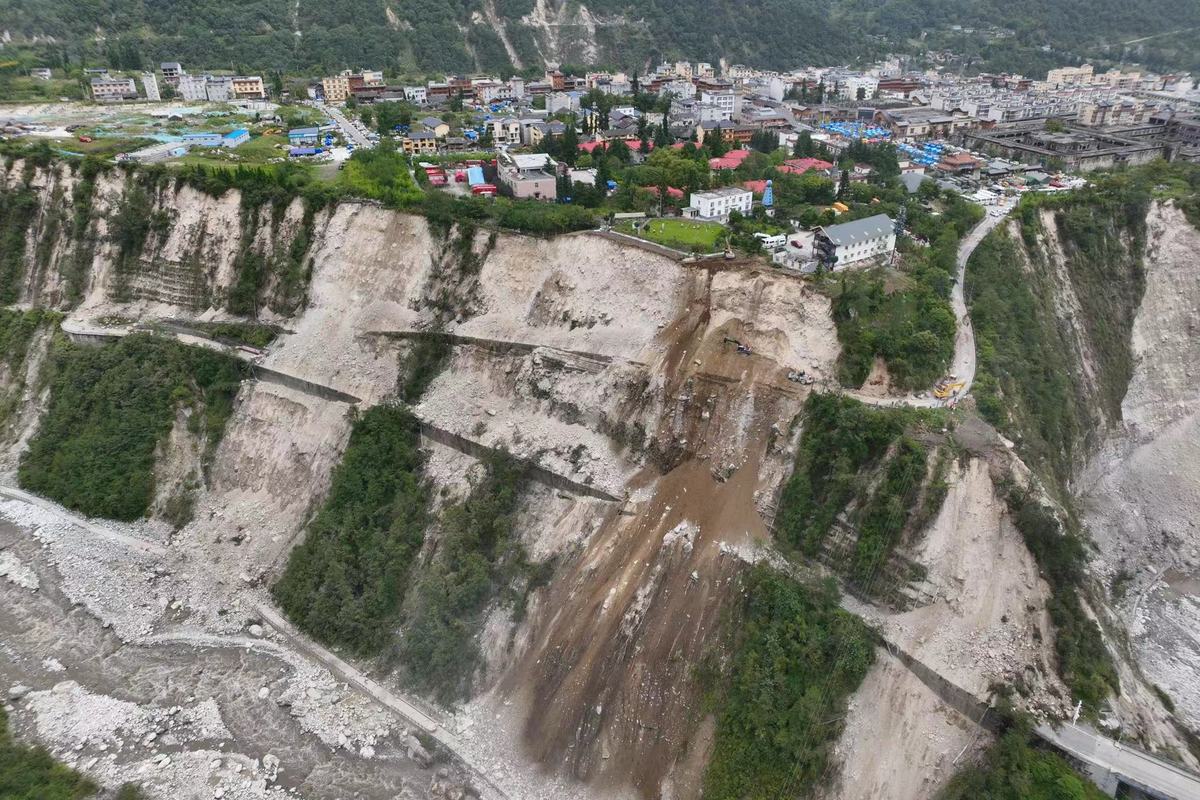 9月6日，泸定县磨西镇通往海螺沟景区的道路被山体滑坡阻断，蜀道集团工作人员通过挖机在绝壁之上全力抢通道路。（杨树 摄）