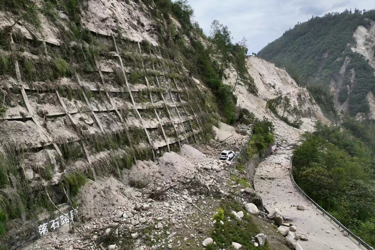 9月6日，泸定县磨西镇通往海螺沟景区的道路被山体滑坡阻断，有一辆私家车被困，目前已被救援转出。（杨树 摄）