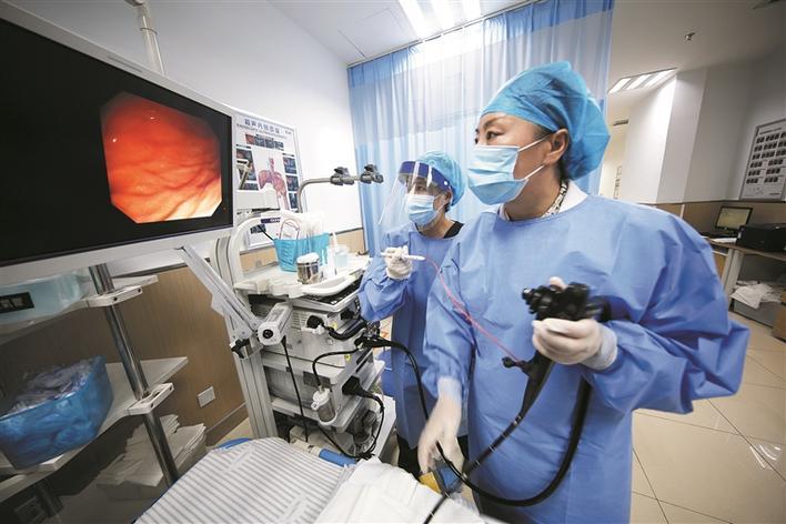 8月14日,杨红伟(前)为患者做肠胃镜检查.张启鹏 摄