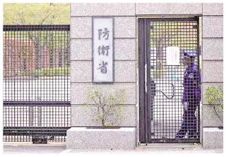 图为在日本东京的防卫省总部，一名工作人员在大门旁守卫。 新华社发