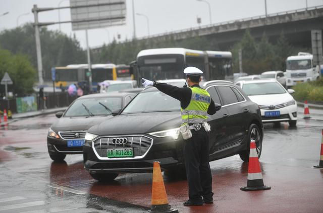今天8点半，香泉环岛车流增长明显，交警在雨中疏导交通。新京报记者 王贵彬 摄