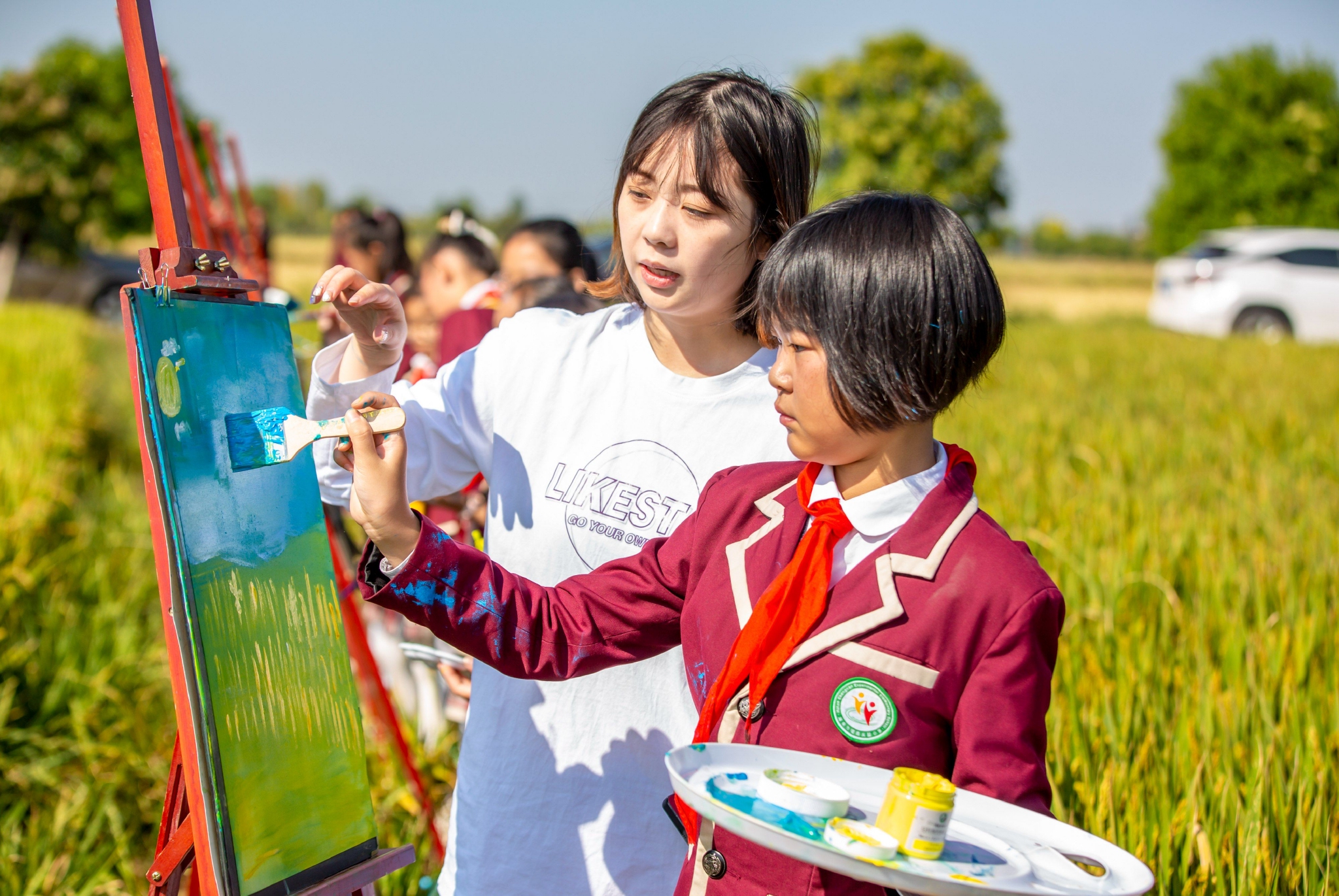 学生们在金黄色的稻田用画笔描绘家乡丰收美景。通讯员 翟慧勇 摄
