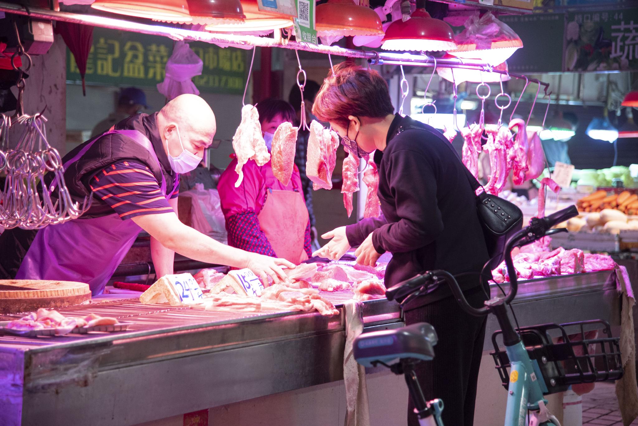 堑口肉菜市场内，一位女士在挑选晚饭要用的肉 时代周报 黄亮/摄