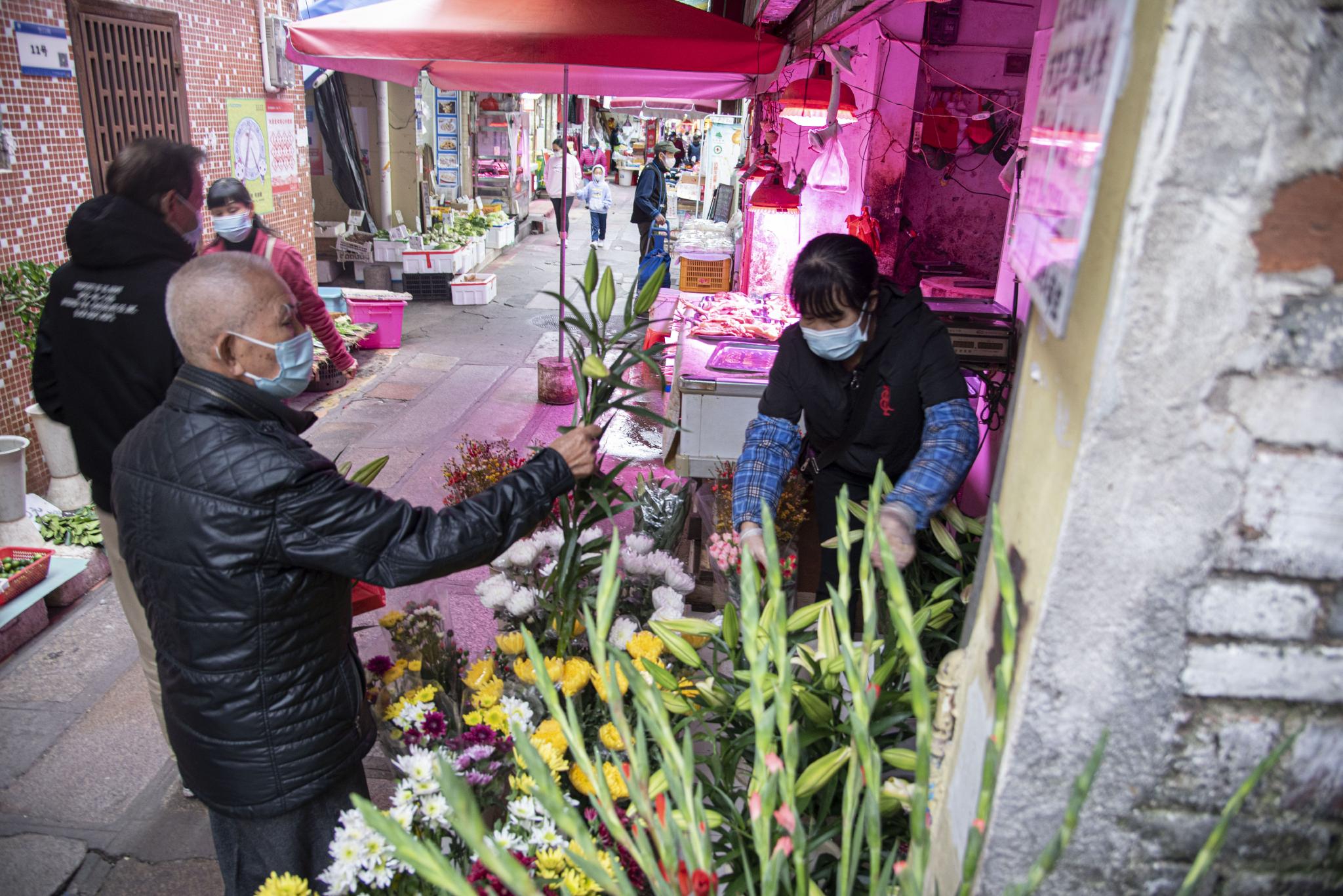 堑口肉菜市场旁的小巷，一位大叔在仔细地挑选着百合花 时代周报 黄亮/摄