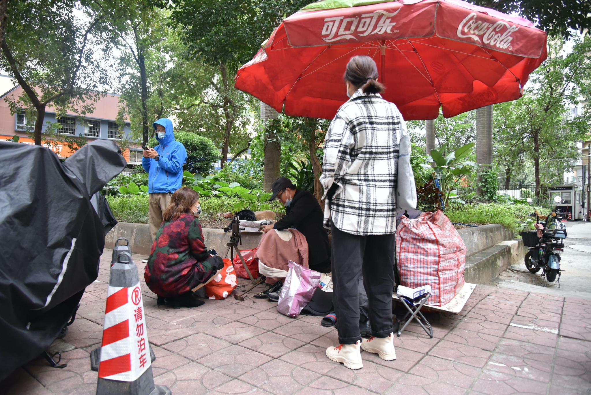 江南西地铁站旁的小区内，人们围在修鞋铺旁 时代周报 黄亮/摄