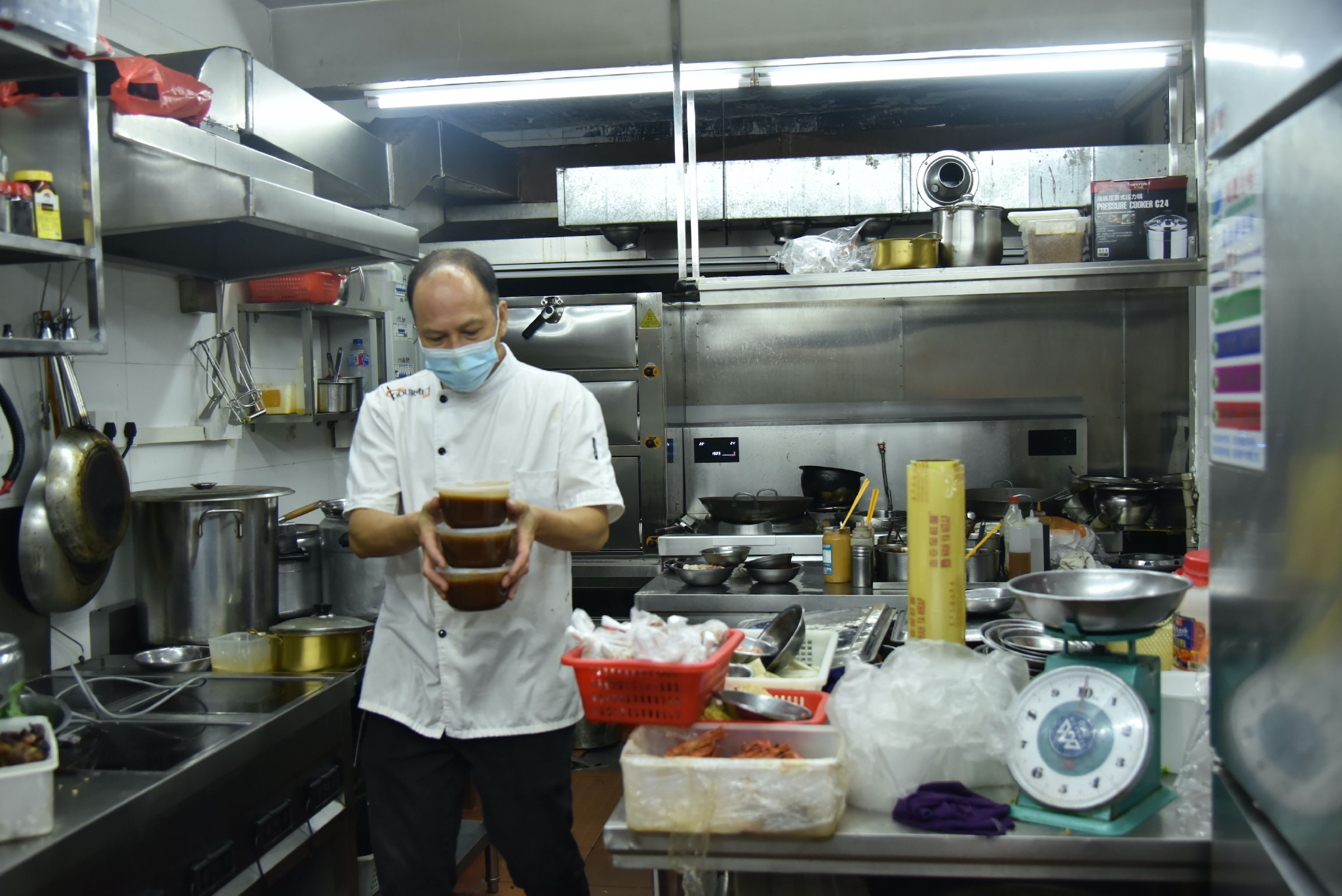 紫丹大街饭店的后厨内，大厨在准备周围老街坊订的菜 时代周报 黄亮/摄