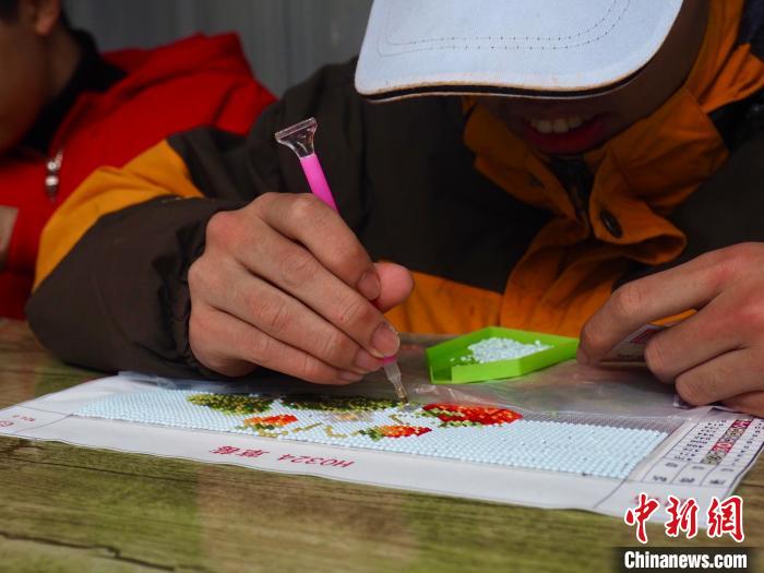 图为一名孤独症患者在制作“钻石画”。李娇阳 摄