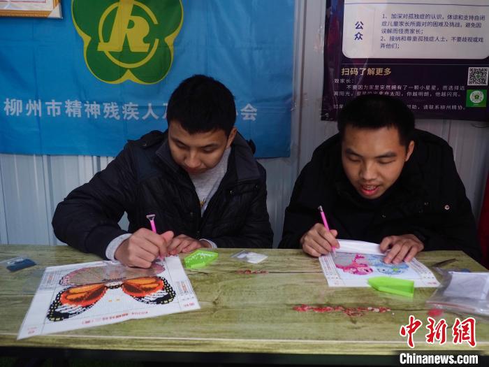 两名孤独症患者在柳州市残疾人就业困难人员创业基地里，制作“钻石画”，其成品在这间店里挂出售卖。李娇阳 摄