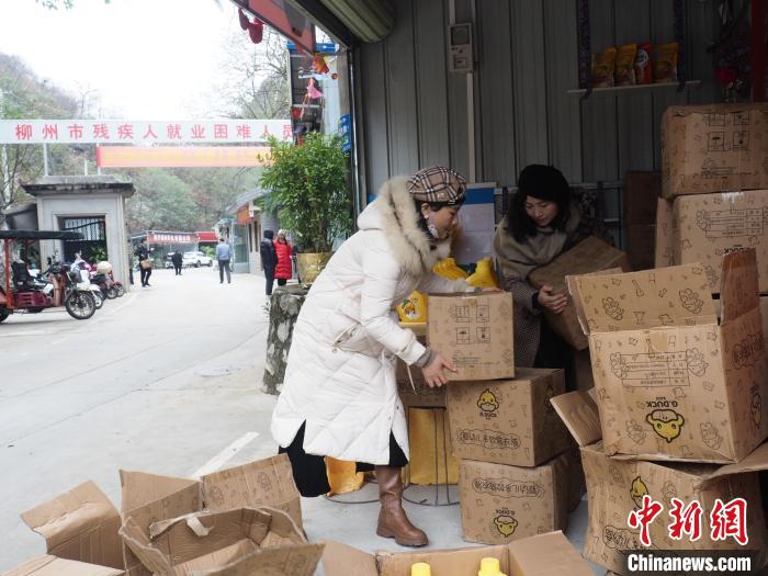 在柳州市残疾人就业困难人员创业基地免费提供的实体门店里，一位戴着义肢的女生(左)在搬运货物。李娇阳 摄