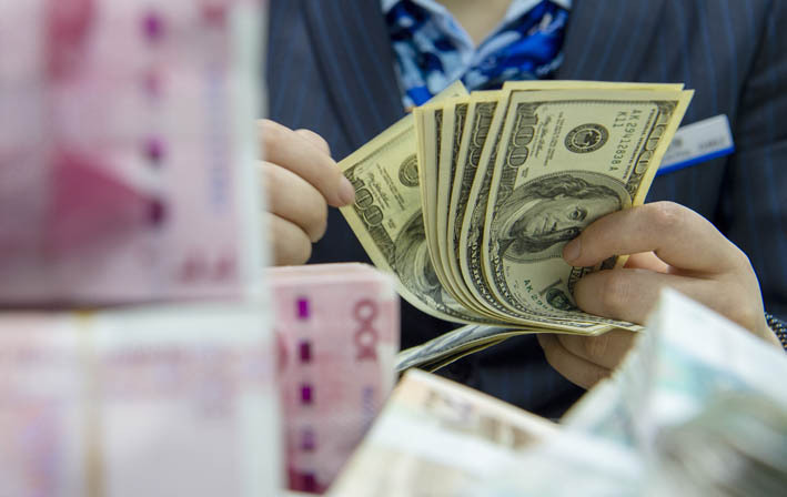 11月末外储规模环比上升2.13%。图为江苏省海安市一家银行的工作人员清点美元现钞 新华社图