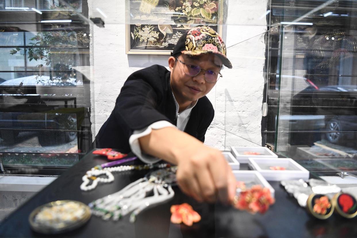 在广州市荔湾区的工作室,王新元在摆放广绣文创产品(12月6日摄).