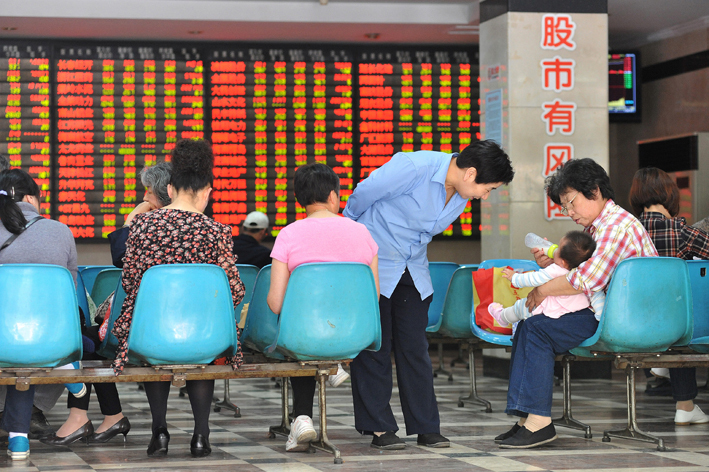 2014年5月12日，南京某证券营业部一位股民正在用奶瓶给孩子喂奶 视觉中国图