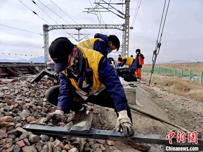 图为西宁电务段职工为道岔杆件清扫油泥.马松摄