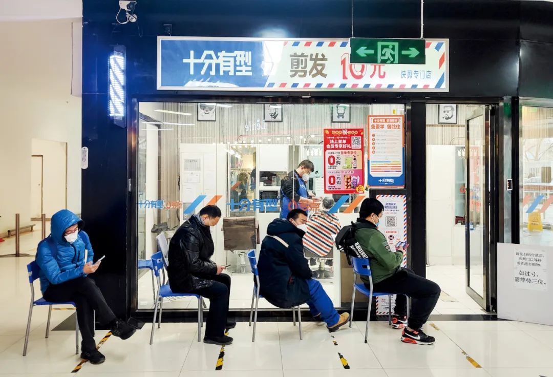 2022年12月25日，北京市朝阳区一理发店门外，人们排队等待理发。摄影/本刊记者 贾天勇