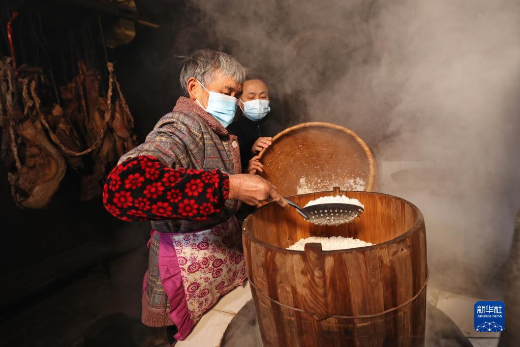 12月27日,岑巩县水尾镇马家寨村村民将泡好的糯米放入甑子蒸煮.