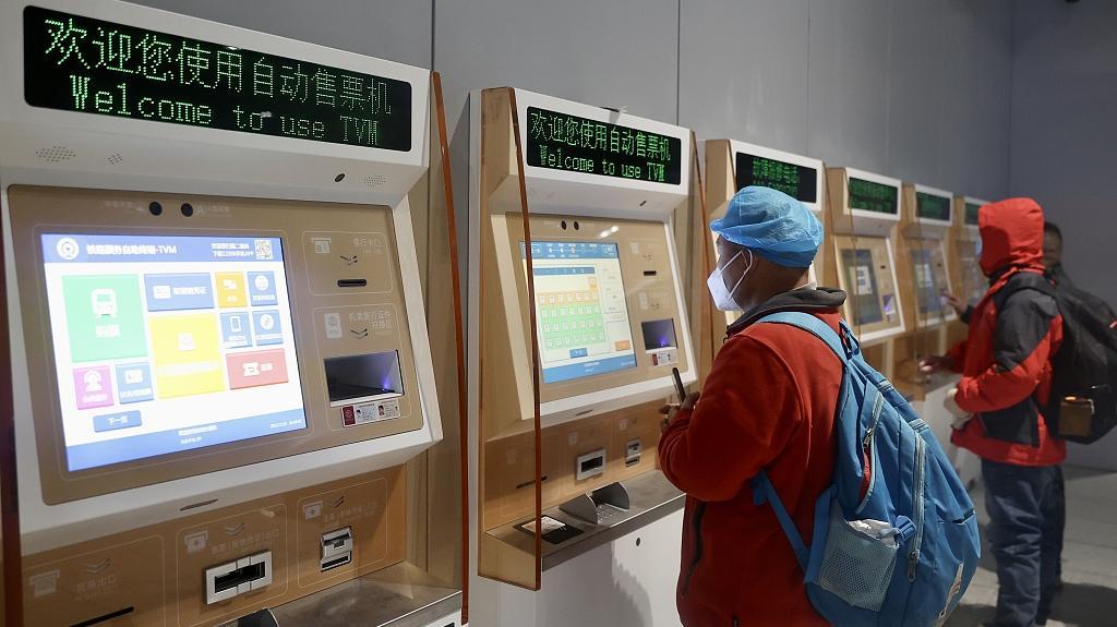 旅客在自动售票机前购买火车票.视觉中国 资料图