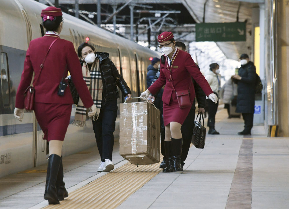 1月7日,在北京西站,g1579次列车的乘务员在发车前帮旅客拿行李.