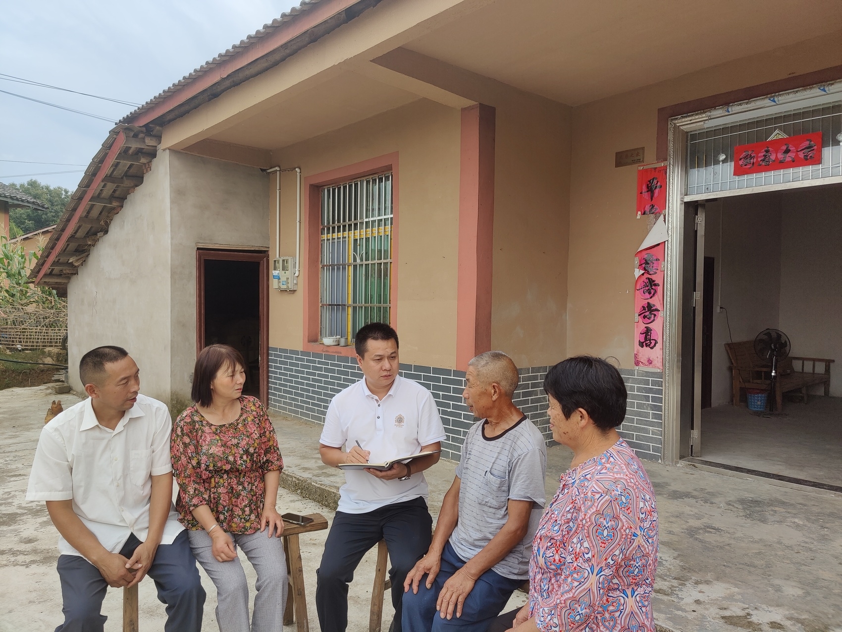 南充市营山县新店镇千坵村党支部书记熊亮(中)正在走村入户,了解村民